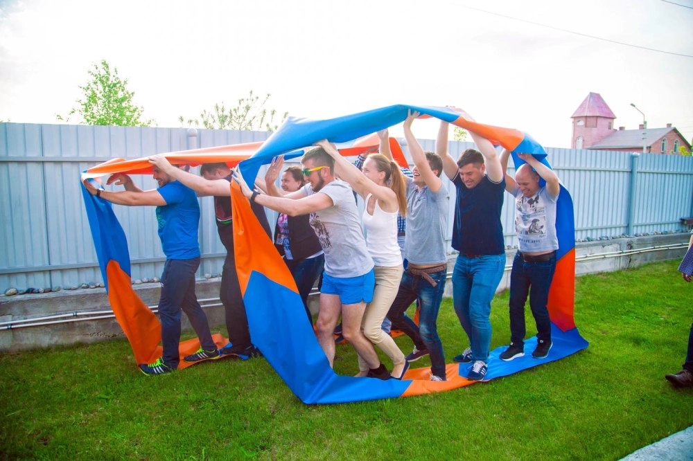 Thành viên công ty cùng nhau tham gia trò chơi vận động bánh xe khổng lồ trên cỏ